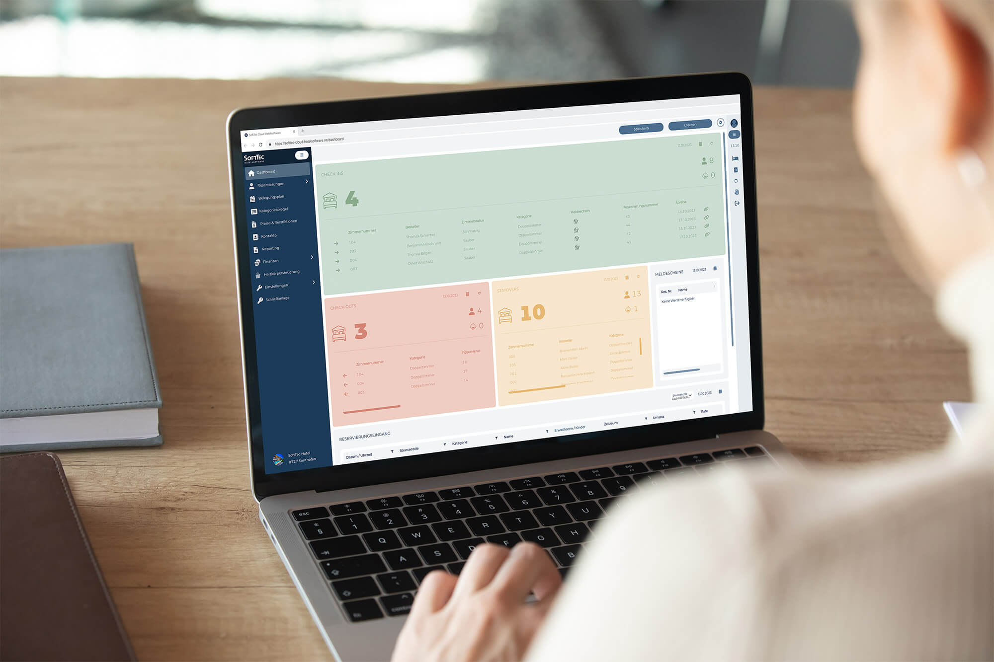 Blick über Schulter einer Frau, die am Schreibtisch am Laptop sitzt, auf dem das Dashboard der SoftTec Cloud Hotelsoftware zu sehen ist